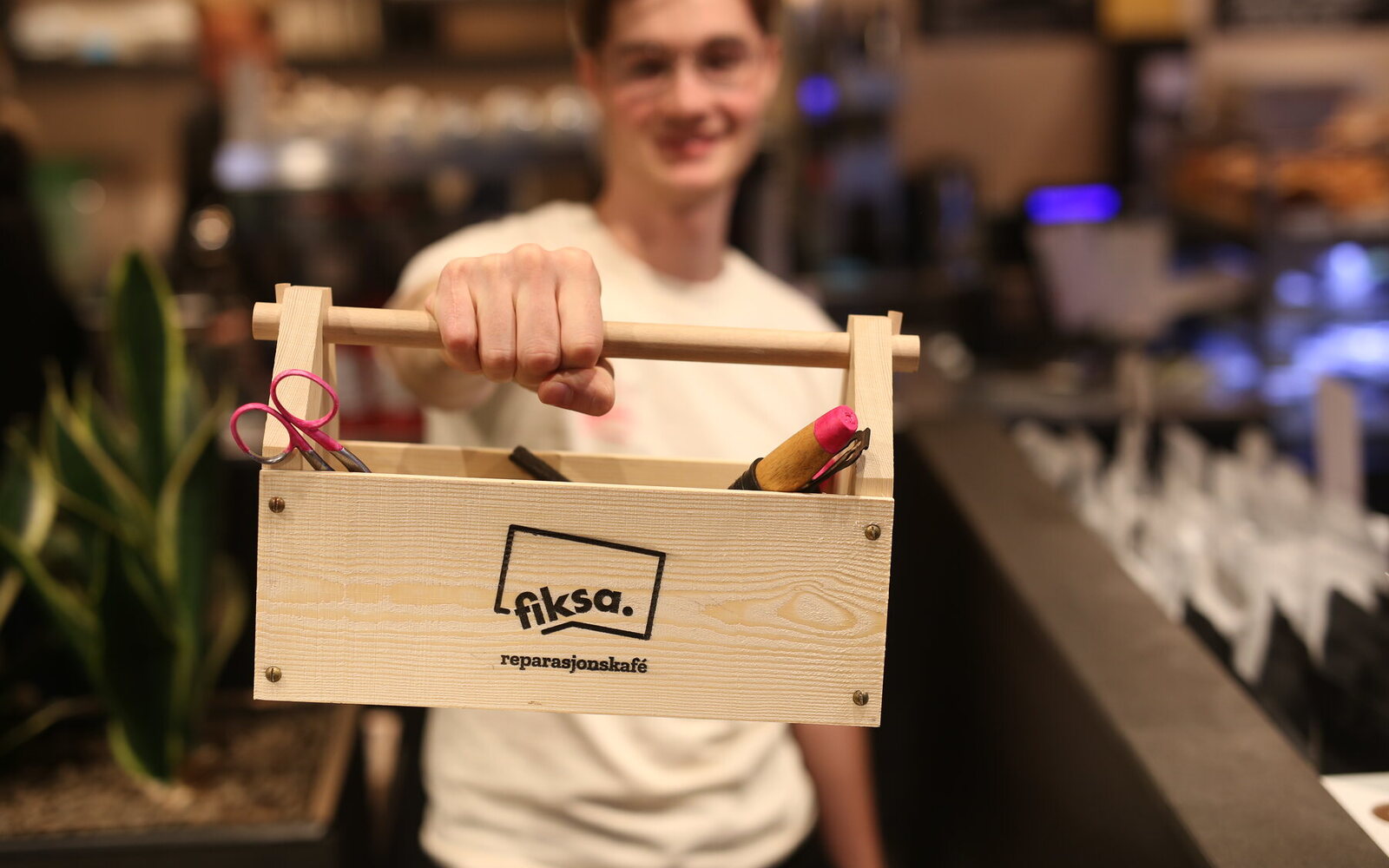 A hand holding the wooden Fiksa toolbox
