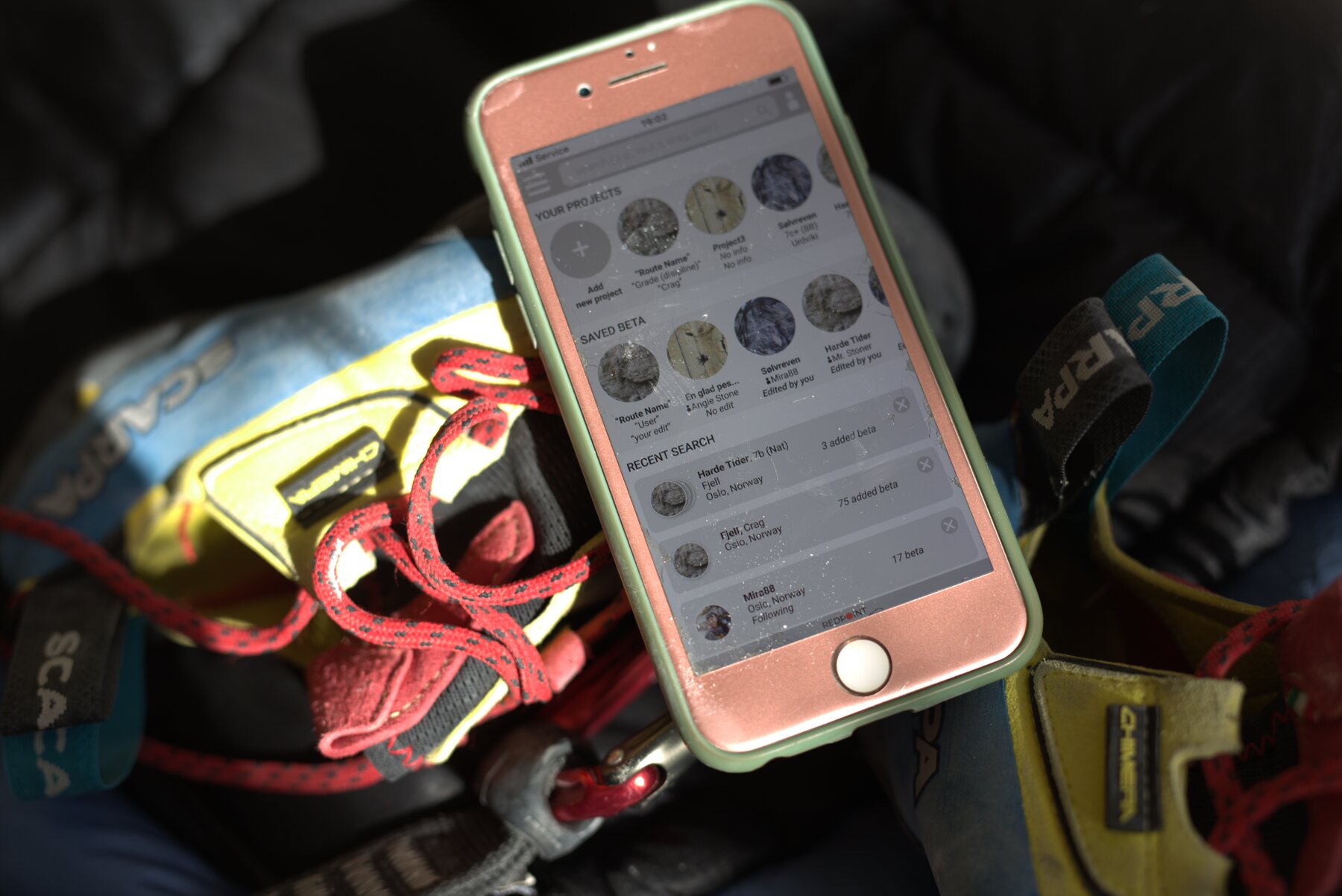 The Redpoint prototype on a phone next to climbing shoes and rope